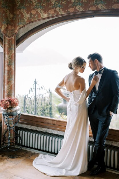 Romantic bride and groom portrait by window with soft natural light elegant indoor wedding photography luxury fine art couple timeless wedding moment