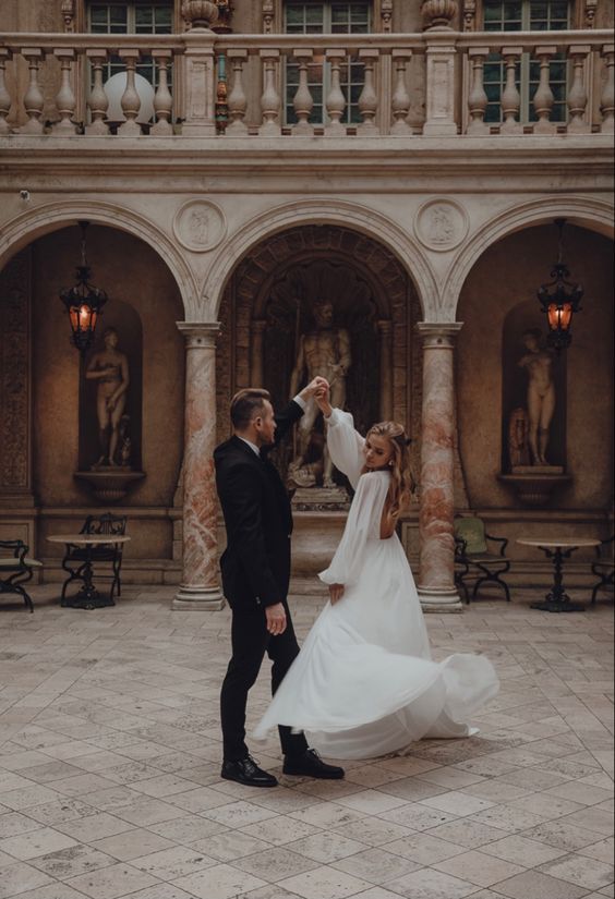 Elegant bride and groom dancing in classic courtyard with arches luxury wedding photography romantic fine art couple portrait timeless architecture backdrop