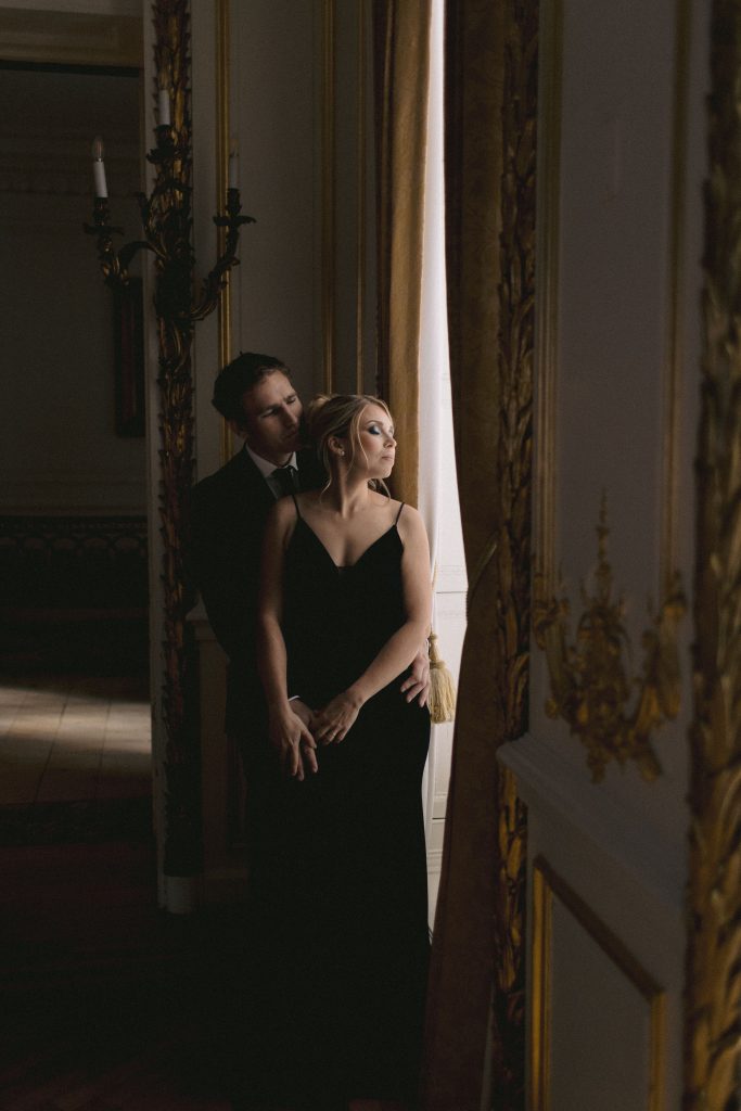 Cinematic wedding portrait of couple in elegant indoor venue with soft window lighting