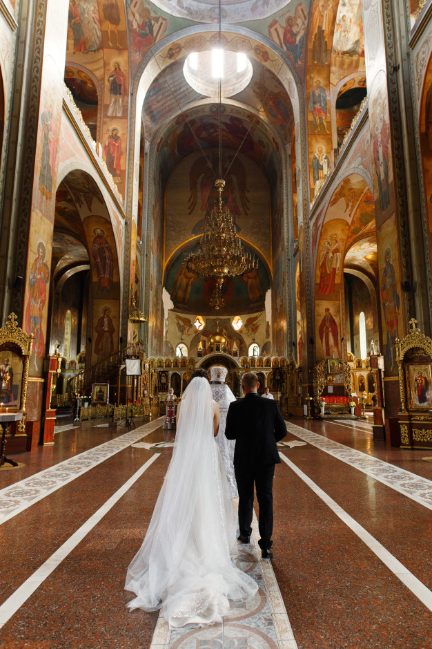 Bride and groom walking down grand cathedral aisle with ornate architecture romantic church wedding ceremony fine art photography