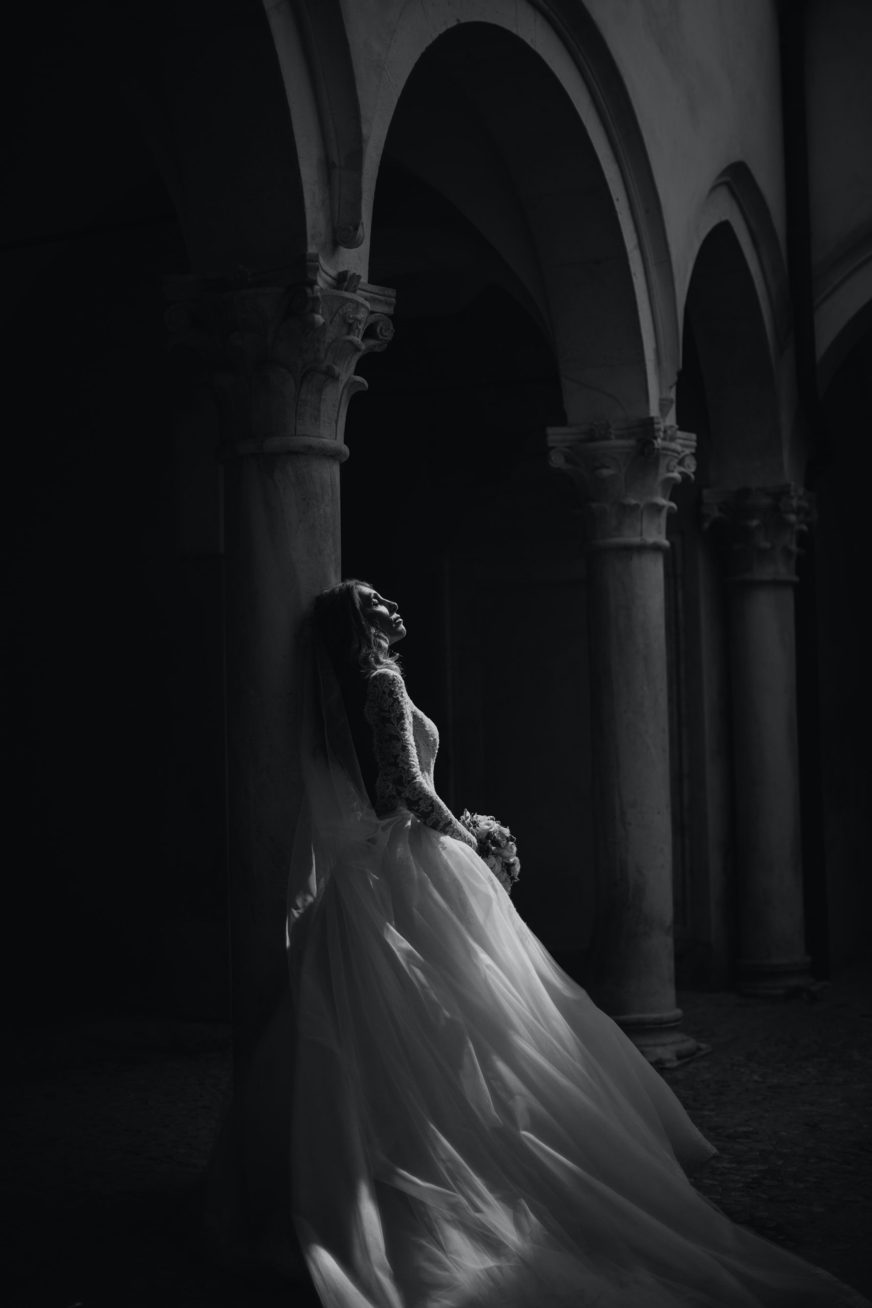 Elegant moody bridal portrait in architectural arches with dramatic lighting fine art wedding photography timeless style