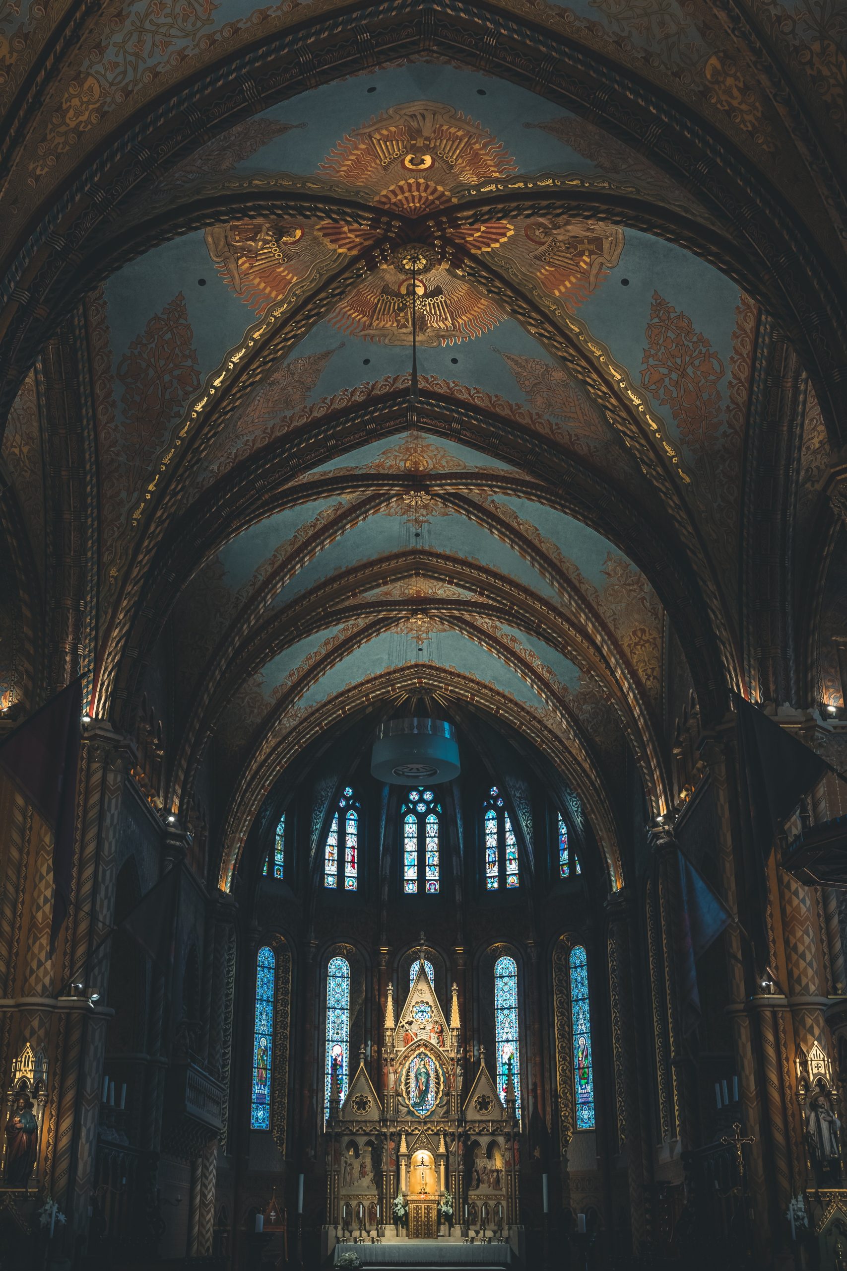 Cathedral wedding venue interior with vaulted arches, painted ceiling, and stained glass altar