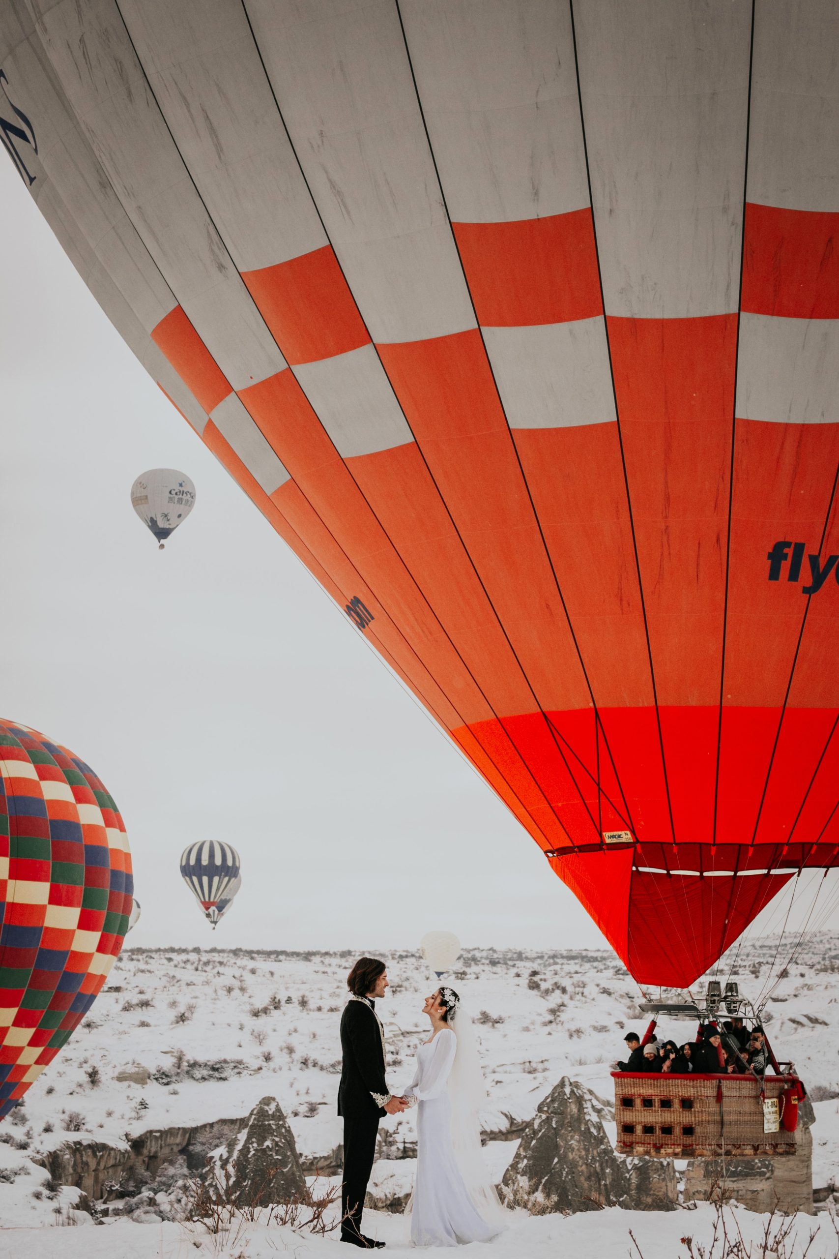 Unique winter wedding couple portrait with hot air balloons in snowy landscape romantic destination wedding photography