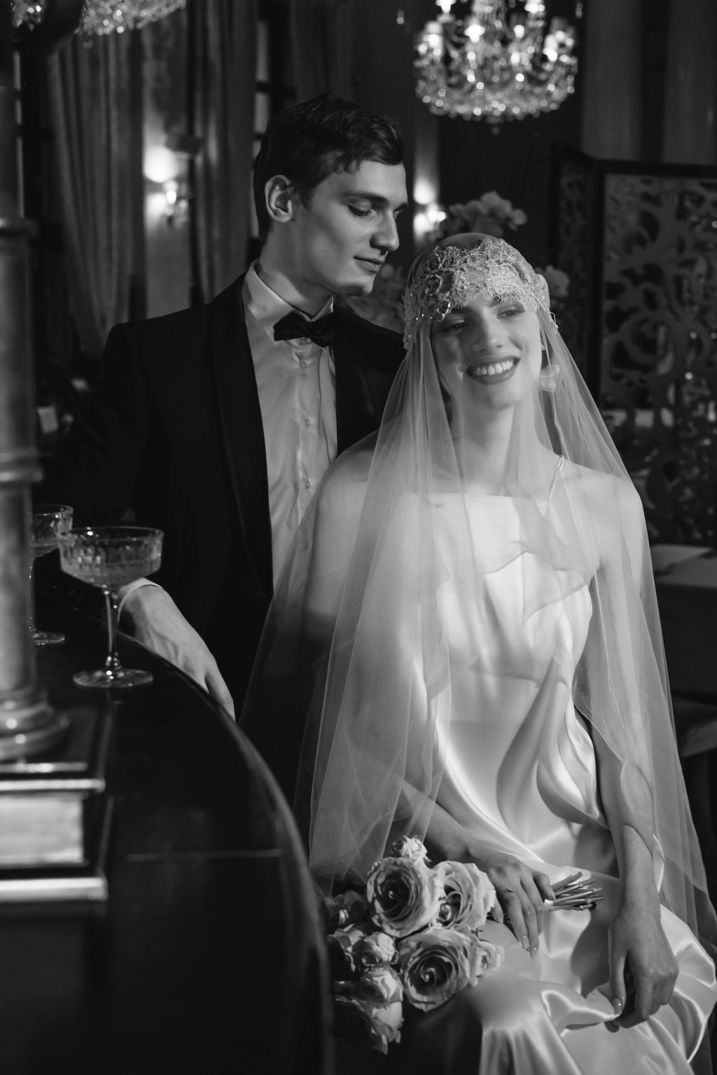 Editorial wedding couple portrait at elegant indoor reception with veil and chandelier lighting